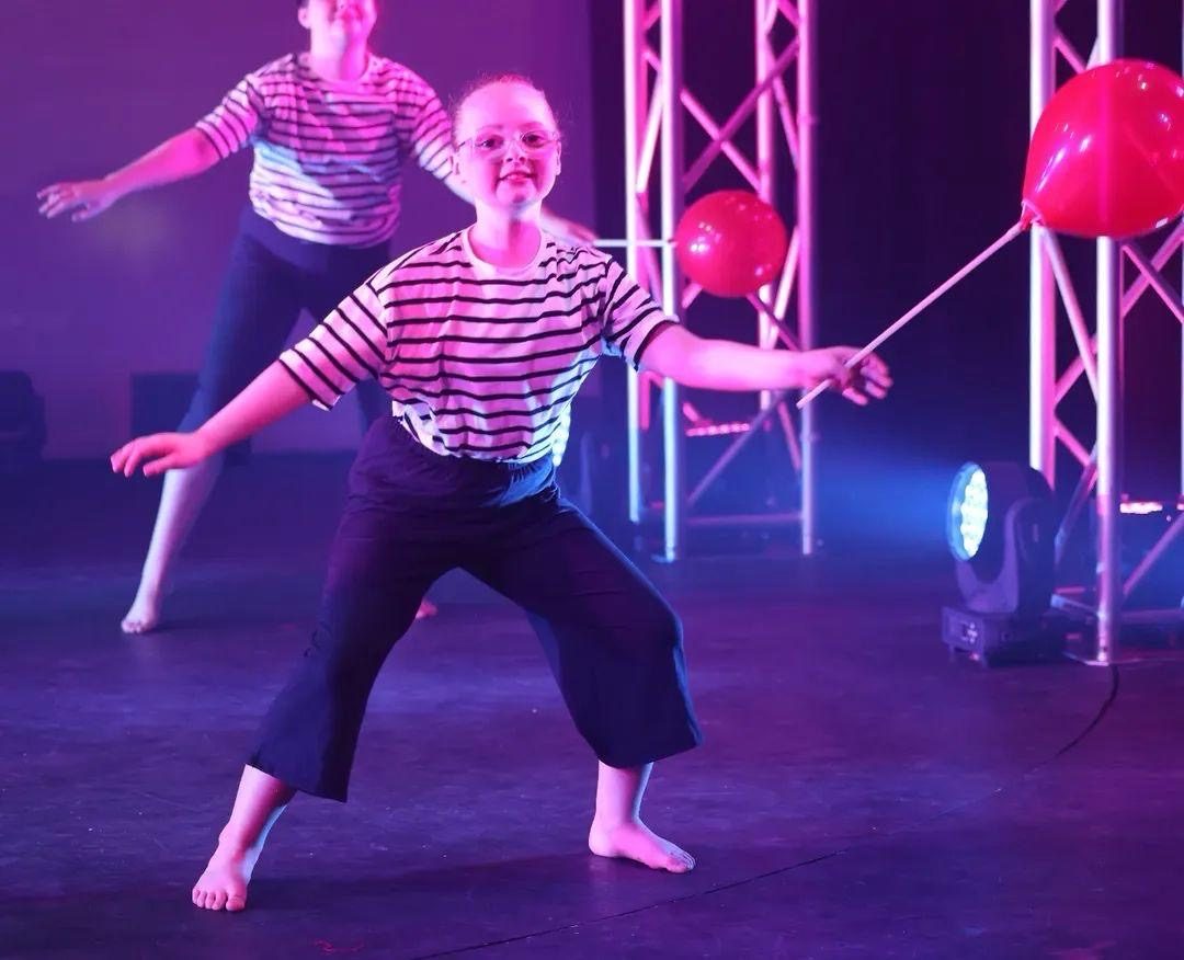 Dancers mid-performance with balloon stage props