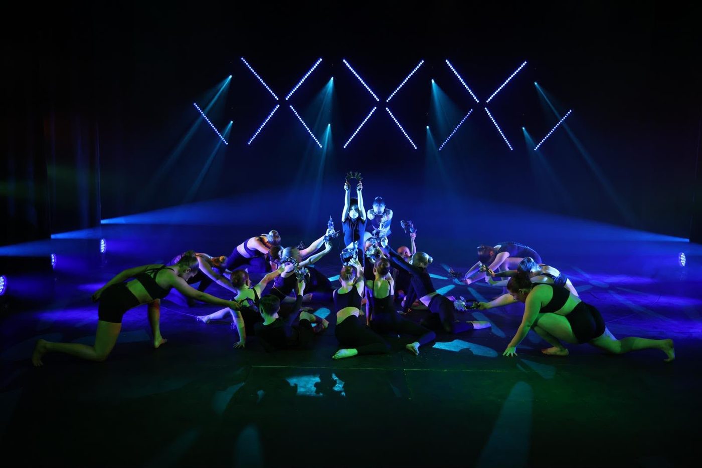 Contemporary dance ensemble performing under blue stage lighting