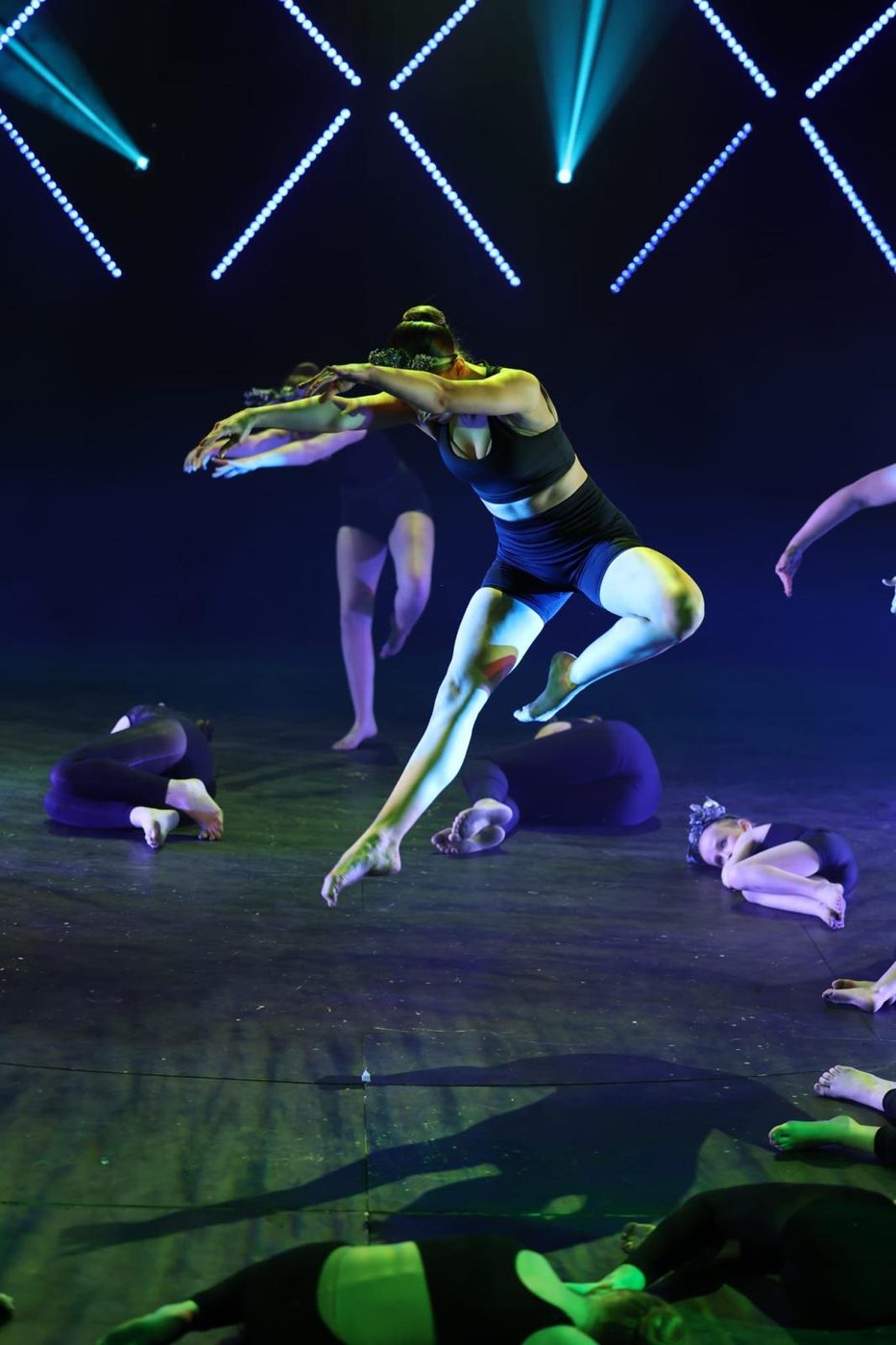 Dancer leaping mid-air during a dramatic contemporary ensemble piece