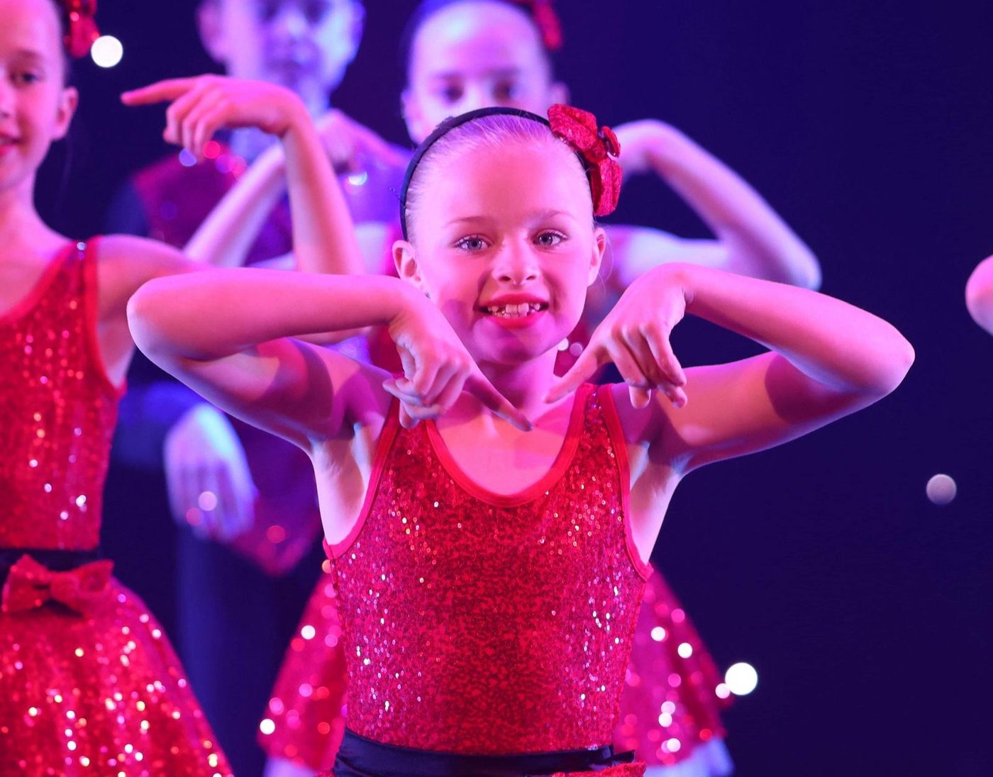 Dancer in red sequins striking a playful pose