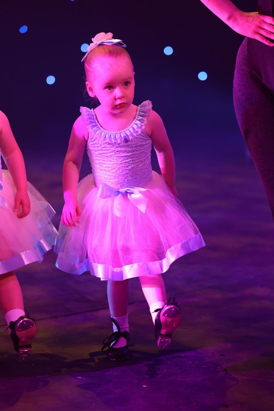Young dancer in a sparkly tutu taking her first steps on stage